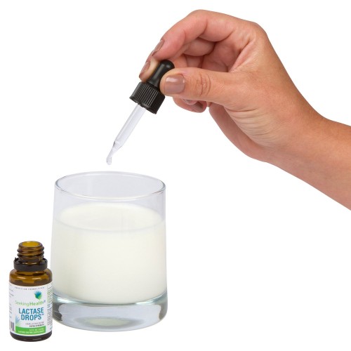 Dropper dripping Lactase Drops into glass of milk